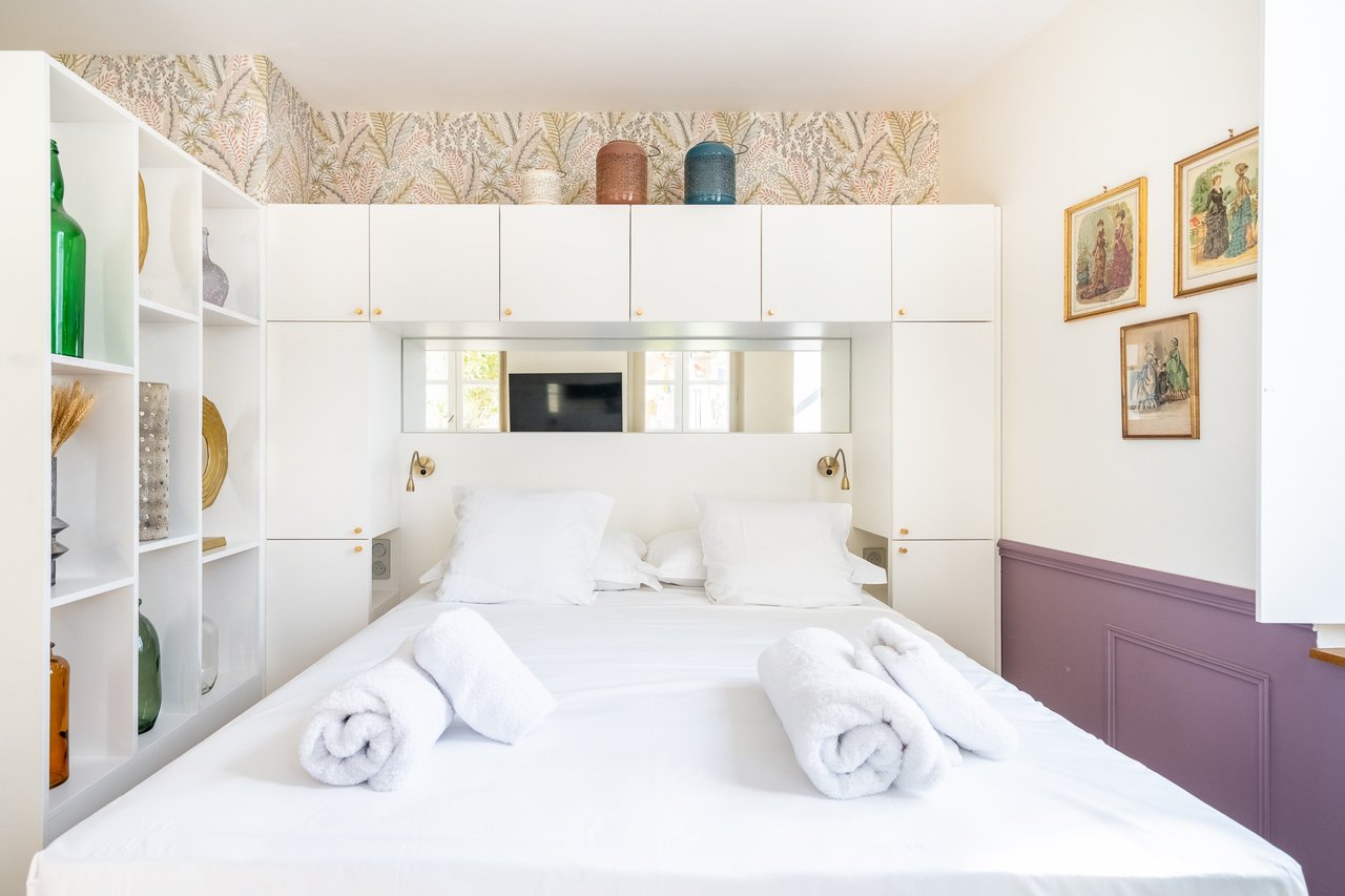 Chambre Deluxe : lit face aux boiseries blanches et au miroir
